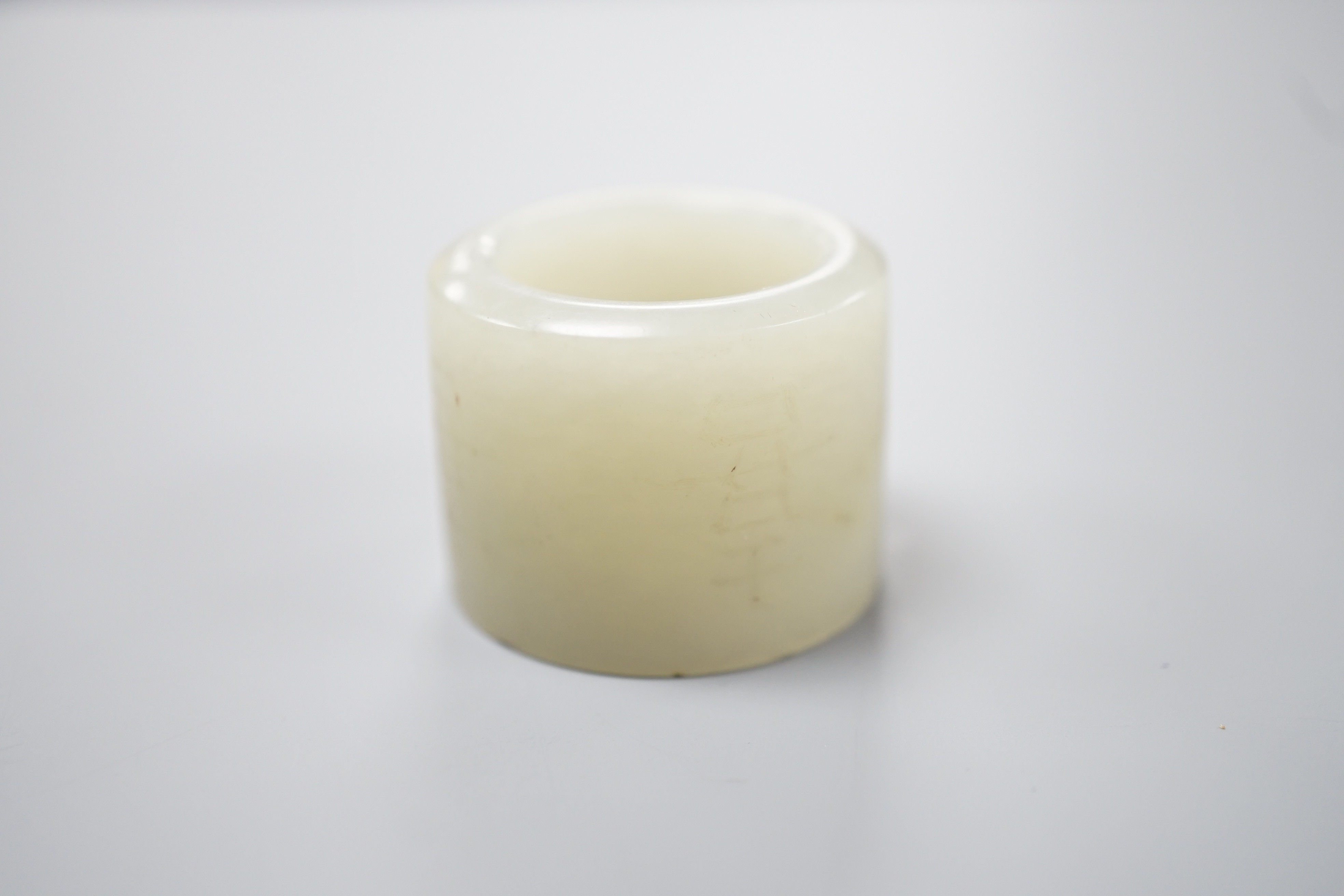 A 19th century Chinese pale celadon jade archer’s thumb ring, inscribed, 3 cm diameter